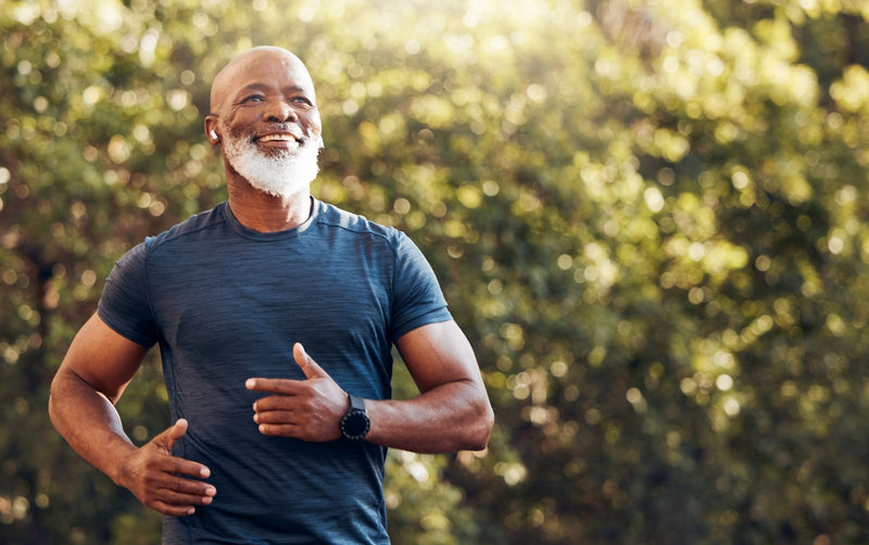 Smiling senior man with a beard jogging in a park, exuding health and vitality.